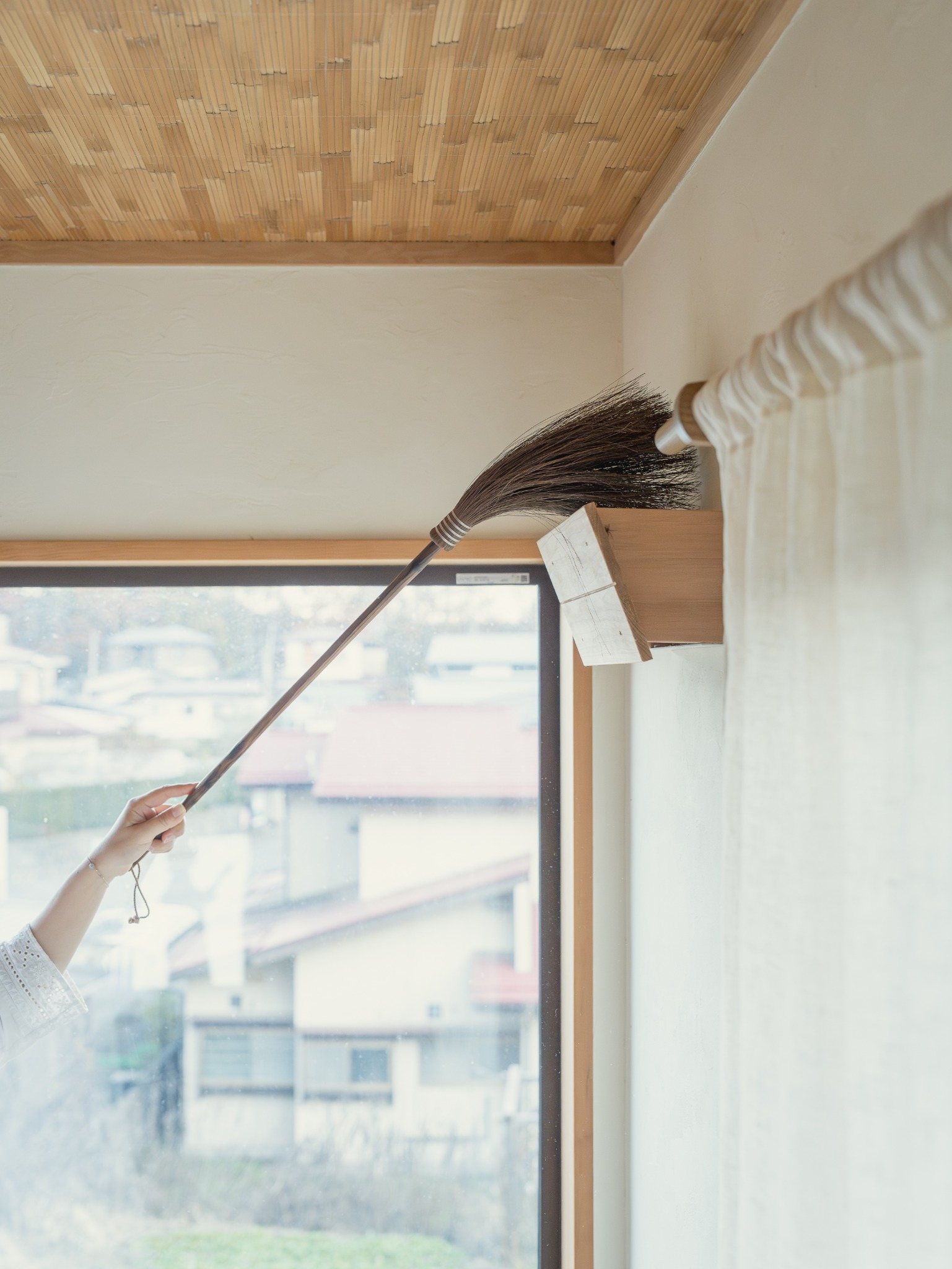 棕櫚ほうきで高い場所を掃除する様子