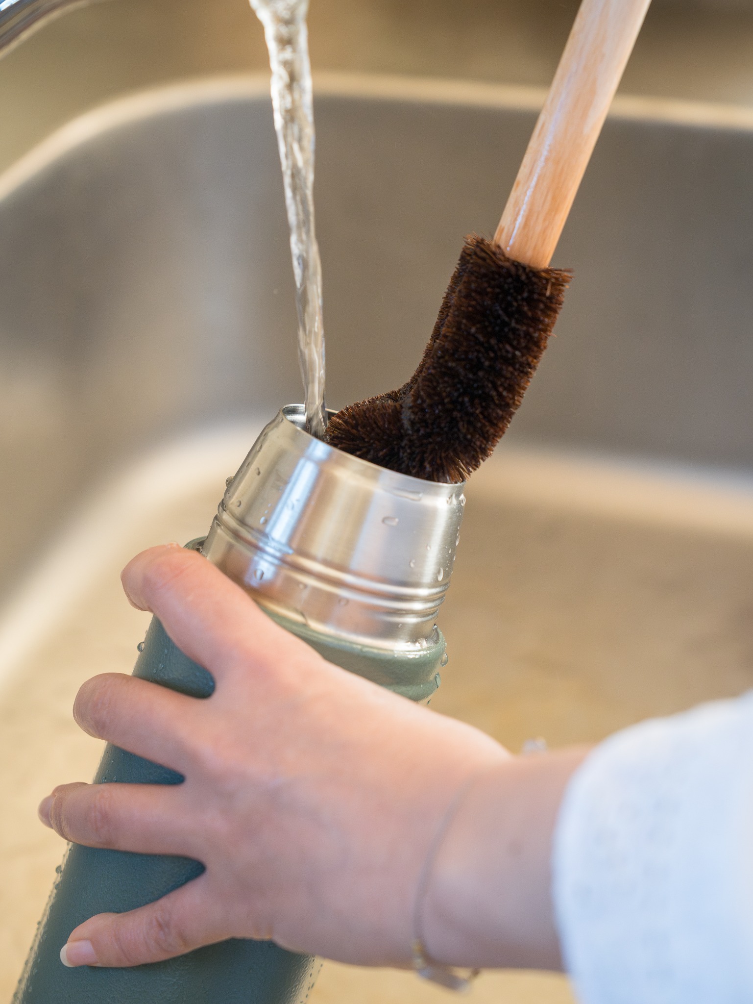 柄付きたわしで水筒を洗う様子